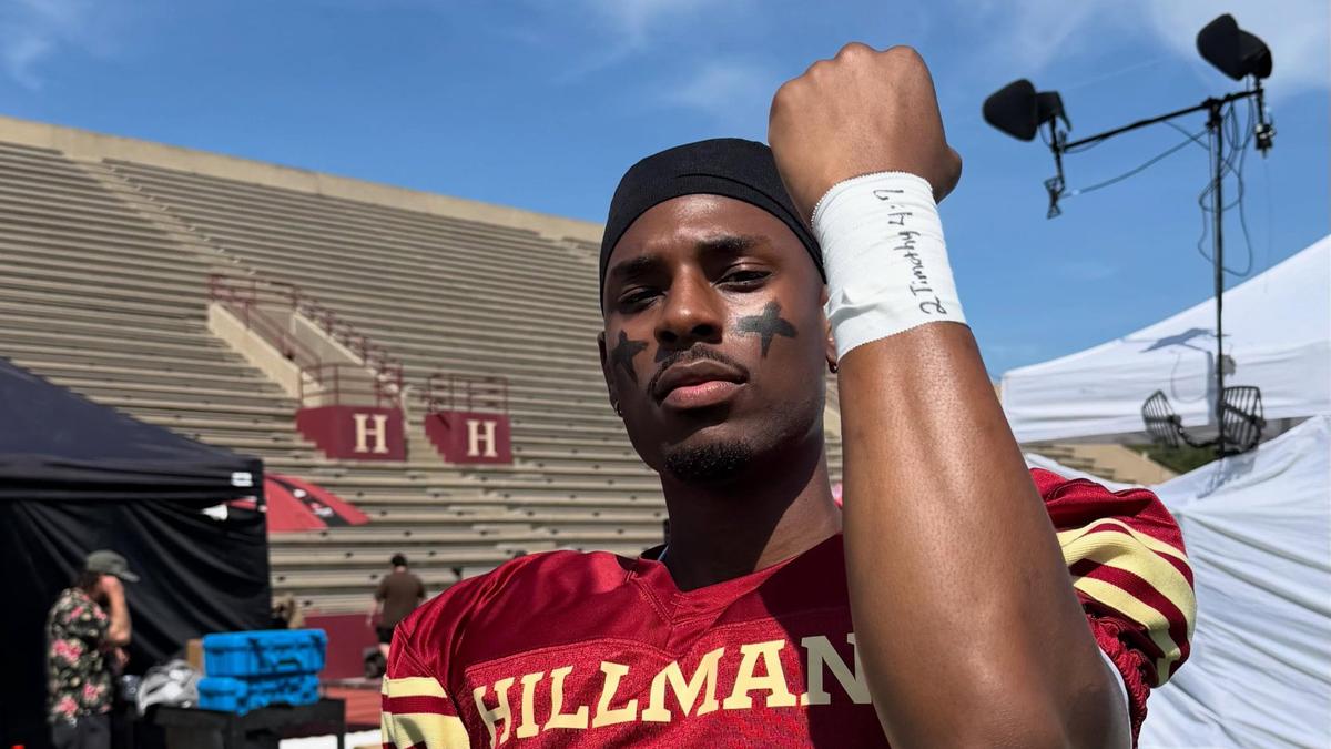 Joshua Suiter raising his fist in a Hillman College No. 7 football jersey on the set of A Different World